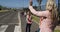 Female teacher waving at two girls while they cross the road