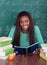 Female teacher writing in book at desk