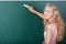 Female Teacher Writing On Chalkboard While Looking Over Shoulder