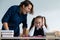 A female teacher yells at a student. Little girl covers her ears with her hands.