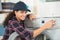 female technician fixes washing machine leak in kitchen