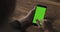 Female teen girl using smartphone with green screen sitting at the table