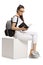 Female teenage student on a cube reading a book