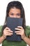 Female teenager hiding hal her face behind book