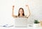 Female teenager learning from home sitting at the desk with arms raised