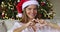 Female teenager in Santa hat making love symbol of fingers