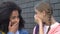 Female teenagers gossiping in schoolyard, spreading rumors about classmates