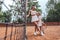 Female tennis instructor with beautiful girl child in white sportswear on tennis court
