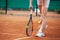 Female tennis player legs in tennis shoes standing on a clay court