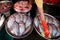 Female Thai vendor with orange latex gloves and sponge cleaning freshwater fish in stainless steel try at the local wet market,