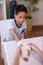 Female therapist wrapping bandage on hand of boy sitting at table