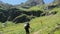 Female tourist backpacker walking with the stick up the mountain