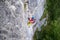Female tourist, in colorful sport clothes, climbs a difficult vertical section on a via ferrata route above Hallstatt, Austria