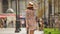 Female tourist in elegant dress, sunglasses and hat checking walking
