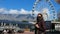 Female tourist with face mask at the Waterfront, with Table Mountain and big ferris wheel