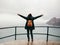 Female tourist with her arms outstretched looking at ocean