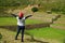 Female tourist raising her arms feeling impressed with Inca stepped agricultural ruins of Tipon archaeological site in Cusco