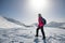 Female tourist in a red jacket goes mountain trail in beautifull winter day.