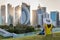 Female tourist sits in a park in front of the skyline of Doha, Qatar