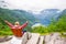 Female tourist sitting on the Queen Sony Chair at the Flydalsjuvet Viewpoint. The Geiranger village and Geirangerfjord landscape.