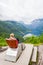 Female tourist sitting on the Queen Sony Chair at the Flydalsjuvet Viewpoint. The Geiranger village and Geirangerfjord landscape.