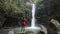 Female tourist standing at the foot of a waterfall enjoying the scenery.