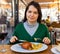 Female tourist tasting Toston asado in restaurant of Salamanca