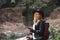 Female tourist use smartphone, with backpack and cowboy hat looking at the river washed away the bridge, the crossing was