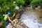 Female tourist with via ferrata gear crossing a cable section above Paraul Racilor in Tureni/Copaceni Gorge, Romania.