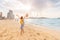 Female tourist walks barefoot on a sandy beach in the JBR area of Dubai and admires the panoramic view of the Ain Ferris