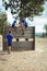 Female trainer assisting fit man to climb over wooden wall during obstacle course