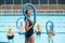 Female trainer and senior swimmers holding pool noodles