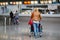 Female travel tourist pushing trolley with luggage at airport terminal. Unrecognizable faceless woman going to airline