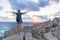 Female traveler, arms rised to the sky, watches a beautiful sunset on spectacular rocks of Capo Testa, Sardinia, Italy.