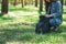 Female traveler with a hat opening her backpack while traveling in a beautiful pine woods