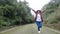 Female traveler running and relaxation on asphalt road among nature around.