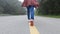 Female traveler running and relaxation on asphalt road among nature around.