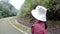 Female traveler running and relaxation on asphalt road among nature around.