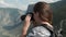 Female traveler takes beautiful pictures using the camera while standing at the peak of the mountain. Close-up