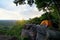 Female Travelers Pitch Vibrant Orange Tent on Cliff with a Natural View. Sitting Relax on Cliff, Embracing Pristine Natural Views