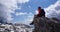 Female trekker sitting on the rick with beautiful landscape back