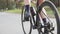 Female triathlete cycling girl pedalling bicycle in park. Close up pedals in motion. Triathlon concept.