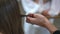 A female trichologist gently takes a strand of hair from the patient's head into her hand and gently runs her hand