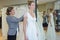 Female trying wedding dress in shop with shop assistant