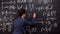 Female tutor writing formula on chalkboard, mathematics lecture, exact sciences