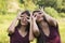 Female twins look through fingers