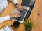 Female typing on laptop keyboard on wooden worktable with supplies