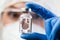 Female UK lab scientist doctor holding glass ampoule vial containing Coronavirus molecule cell