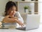 Female university student with laptop and stack of books online studying in living room