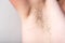 Female unshaved armpits, depilation, hair removal concept on grey background.